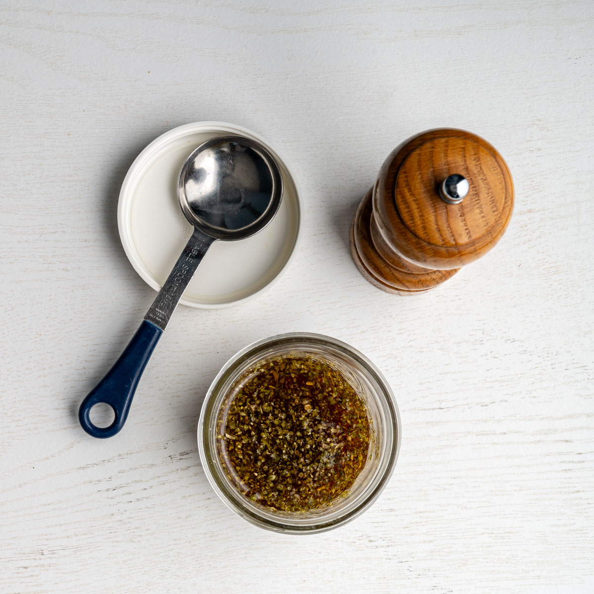 dressing in a mason jar alongside a pepper mill.