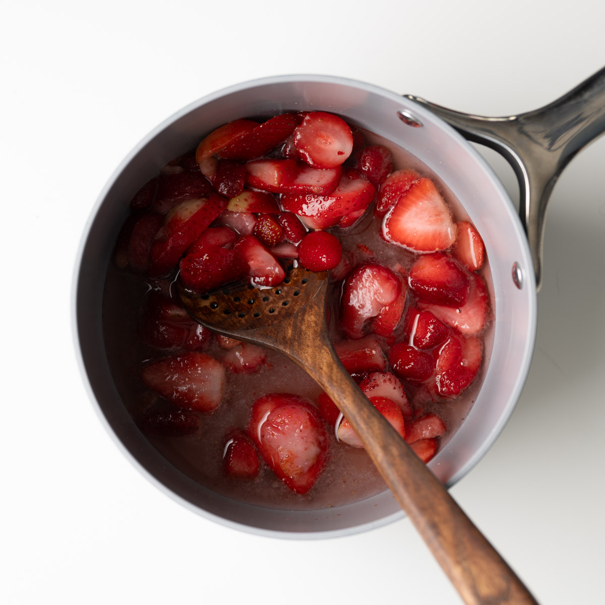strawberries, sugar and water in a saucepan with a wooden spoon.