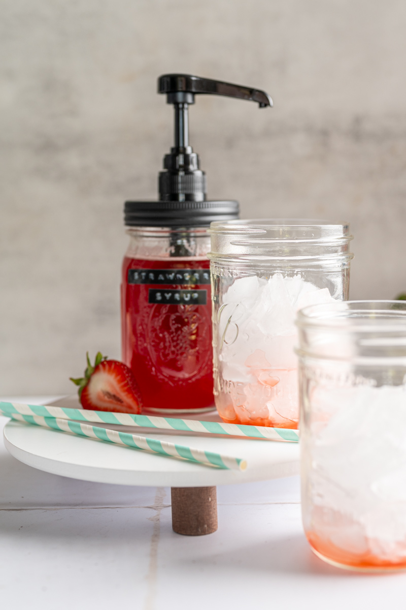 a mason jar pump with two glass of ice with two pumps of strawberry syrup in them.