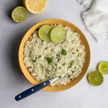 yellow bowl filled with cilatnro lime rice topped with fresh lime slices.