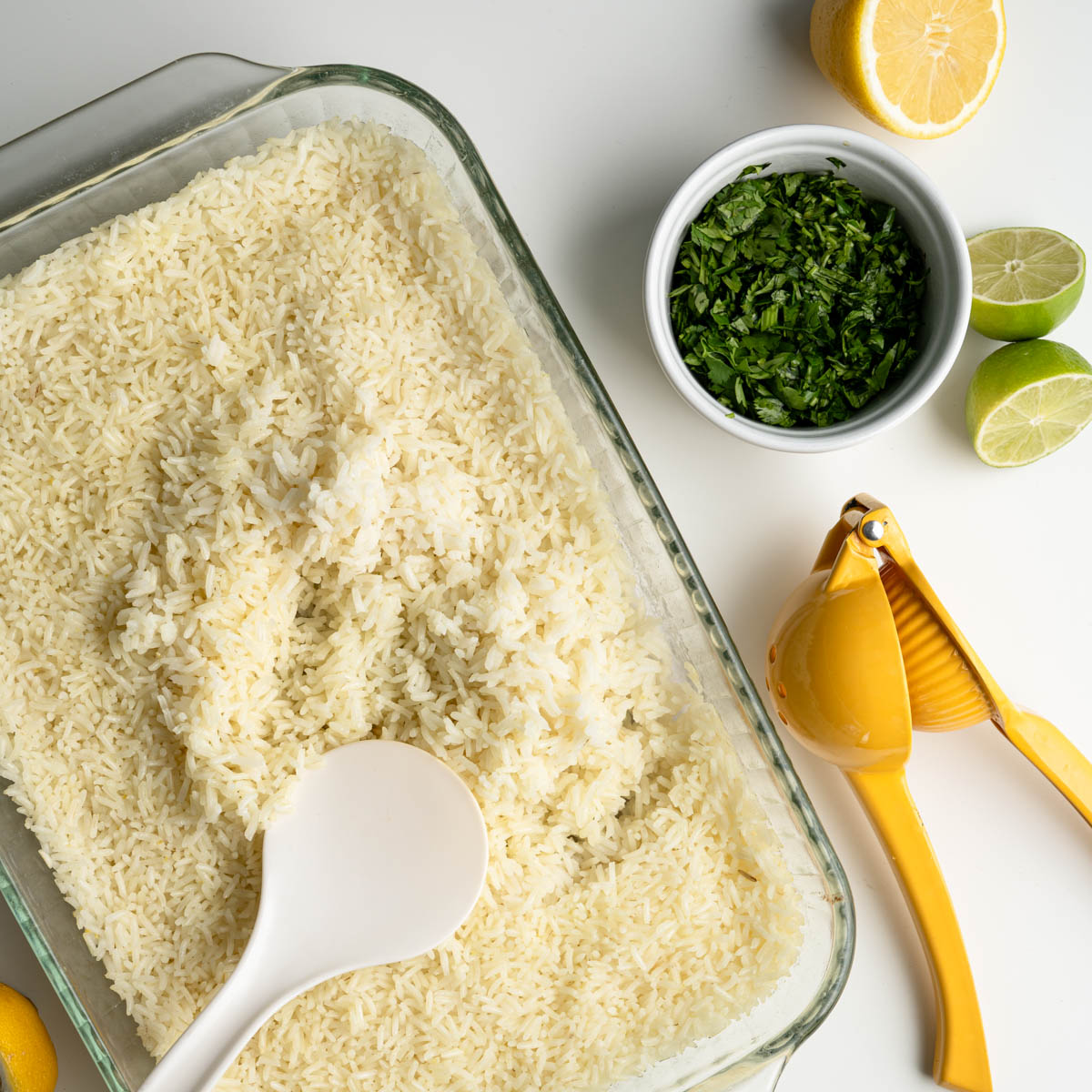 baked rice next to fresh lemon, limes, chopped cilatnro and a citrus juicer.