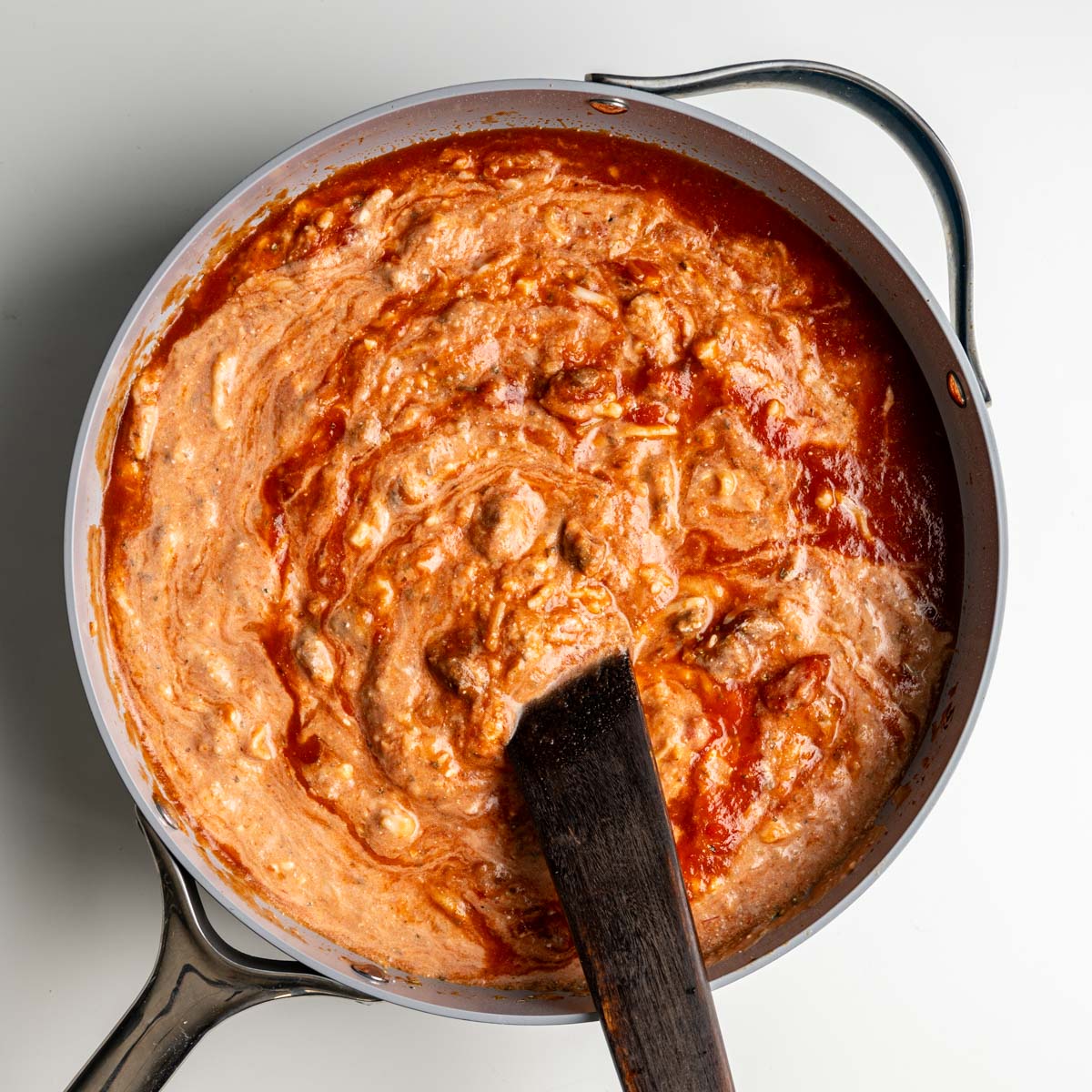cooked sausage, pasta sauce, tomato sauce, shredded mozzarella cheese and spices mixed in a pan.