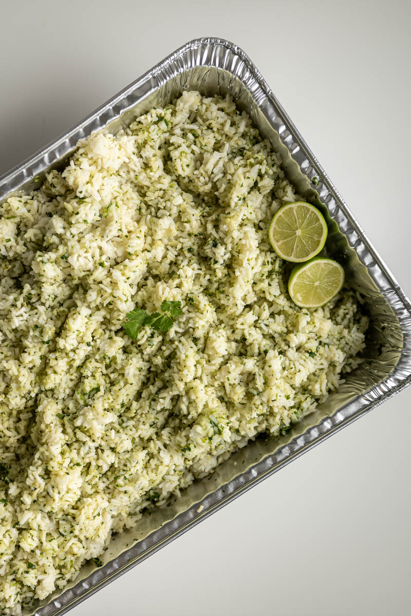cilantro lime rice in a disposable pan topped with lime slices.