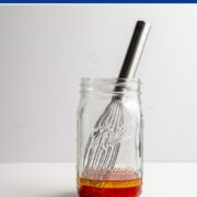 mason jar with a whisk with the ingredients to make a strawberry vinaigrette.