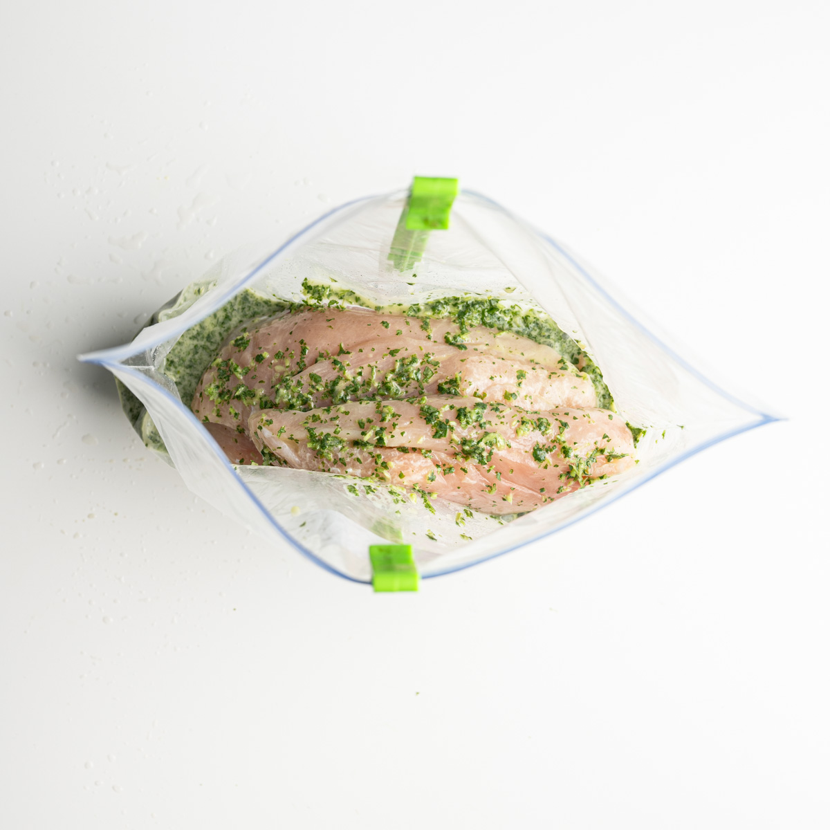 marinated chicken breasts in a zip top bag with a plastic holder.