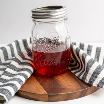 pint sized mason jar with strawberry vinegar on a wooden board.
