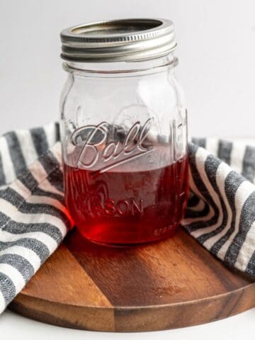 pint sized mason jar with strawberry vinegar on a wooden board.