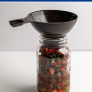 full mason jar with strawberry tops and vinegar with a wide funnel.