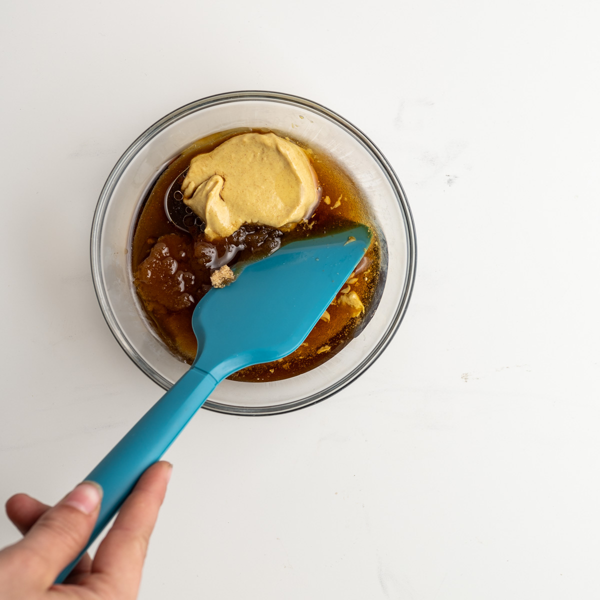 glaze ingredients in a glass bowl with a blue spatula.