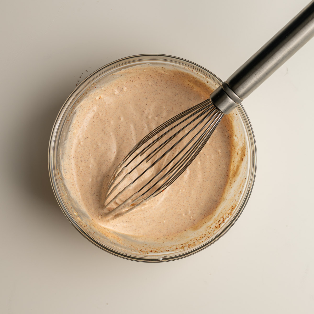 glass bowl with mixed up chipotle sauce and a whisk.