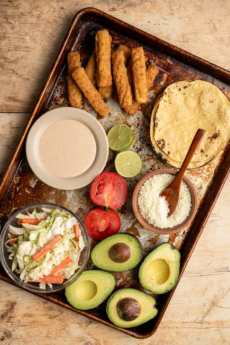 all the components to build fish stick tacos on a baking sheet.