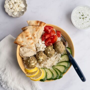 greek chicken meatballs in a rice bowl with other toppings.