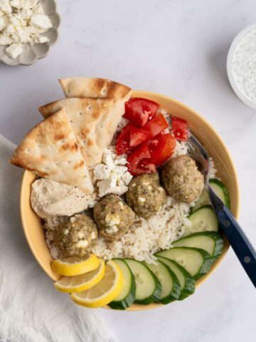 greek chicken meatballs in a rice bowl with other toppings.