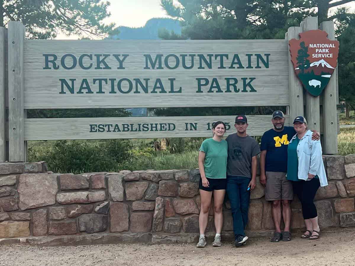 writers family standing in front of the rocky mountain national park sign.