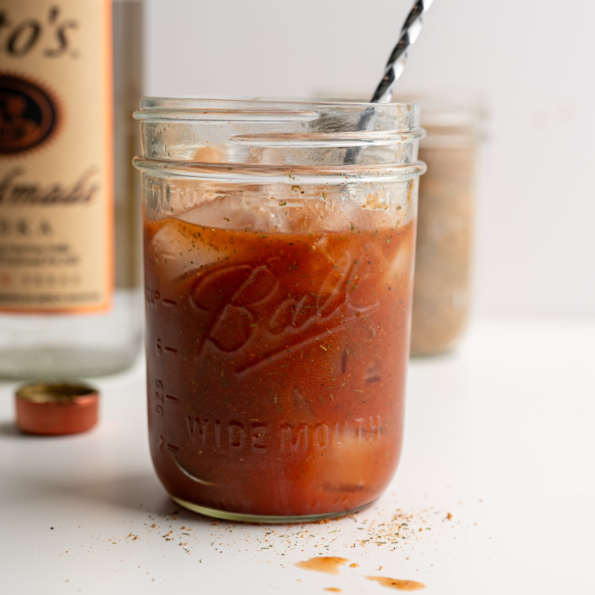 mason jar filled with ice and bloody mary mix with a stir stick.