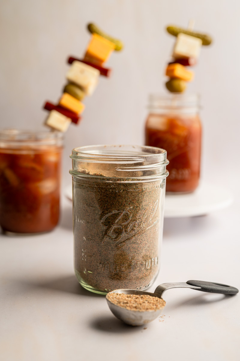 bloody mary seasoning with two bloody mary drinks in the background.