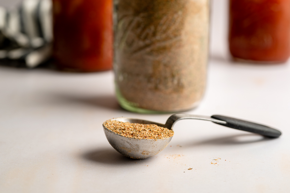 a tablespoon of bloody mary seasoning in front of a jar.