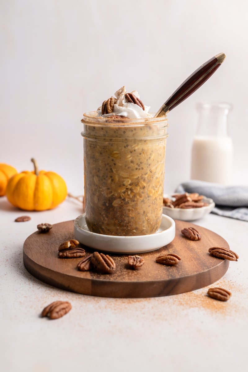 jar of pumpkin overnight oats with coconut whipped cream sprinkled with cinnamon. 