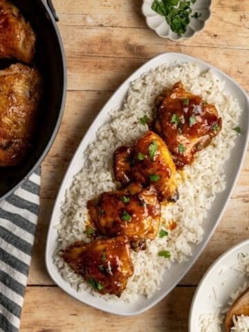 four pieces of baked chicken thighs with apricot curry sauce on a bed of coconut rice.