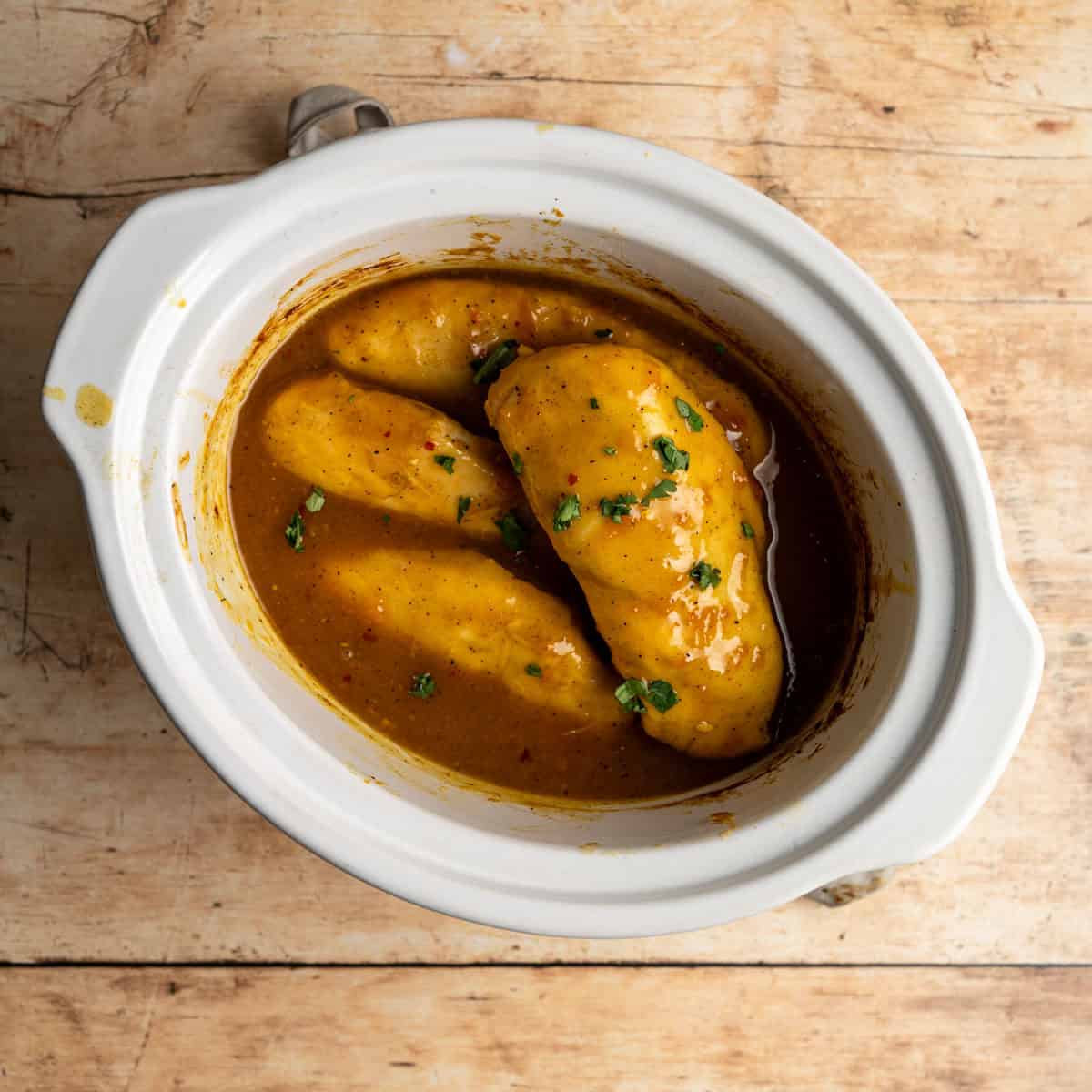 cooked apricot curry chicken in a white crockpot.