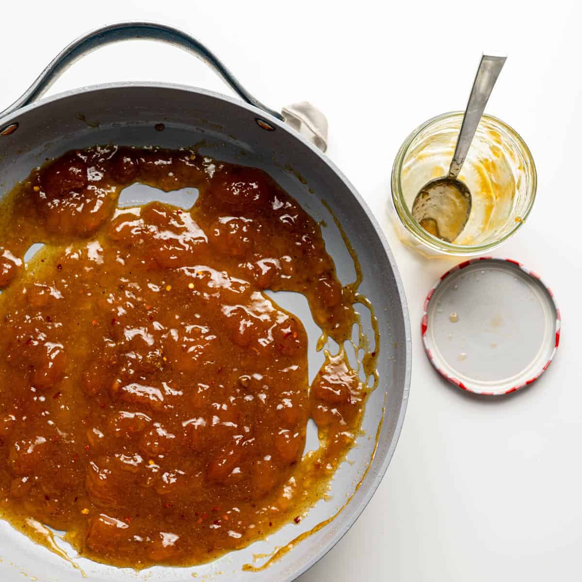apricot sauce in the skillet alongside an empty jar of apricot preserves.