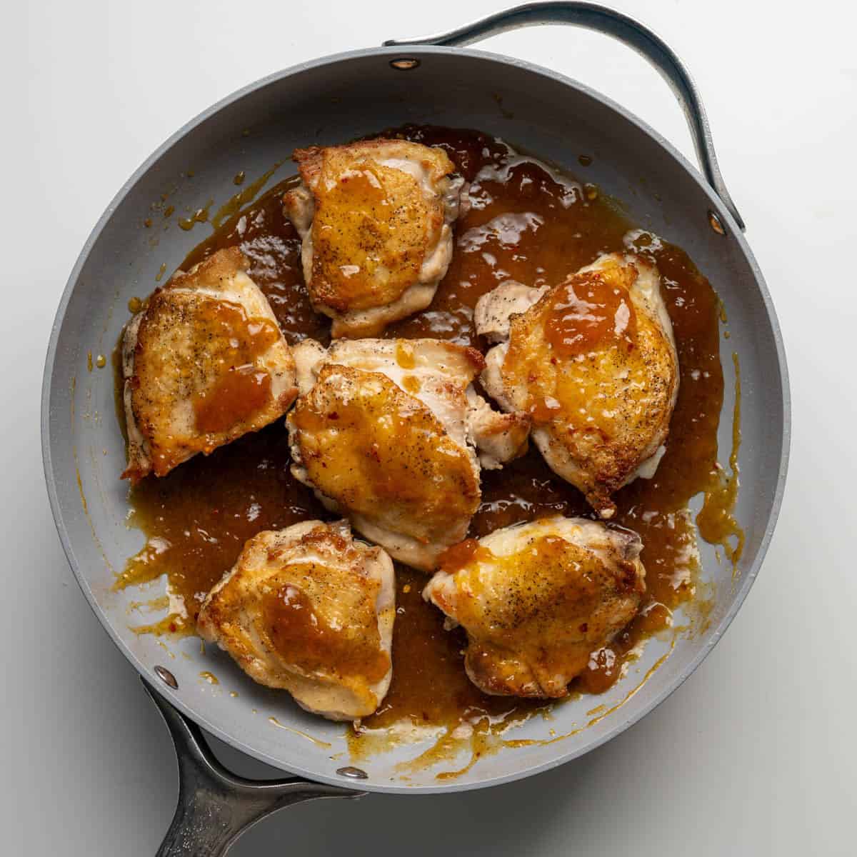 seared chicken thighs on top of apricto sauce unbaked.