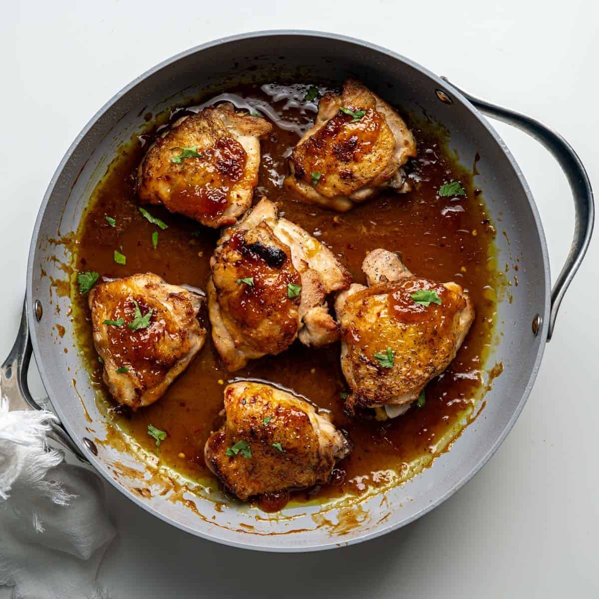 baked chicken thighs in a thickened sauce topped with chopped cilantro in a large skillet.