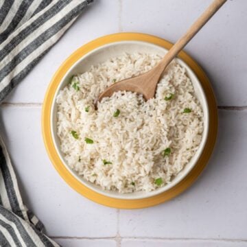 bowl of baked coconut rice with a wooden spoon.
