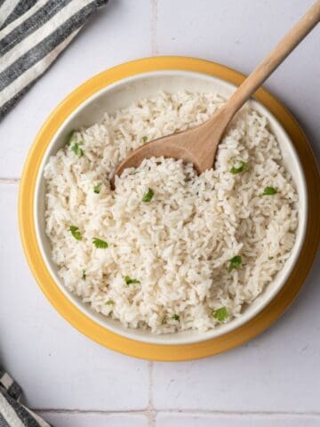 bowl of baked coconut rice with a wooden spoon.