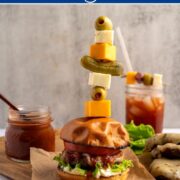 a bloody mary burger with a skewer filled with garnishes.