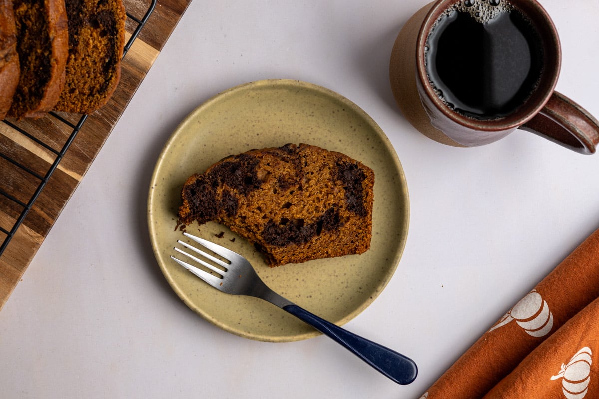 slice of pumpkin bread with a bite missing served on a plate with a fork.