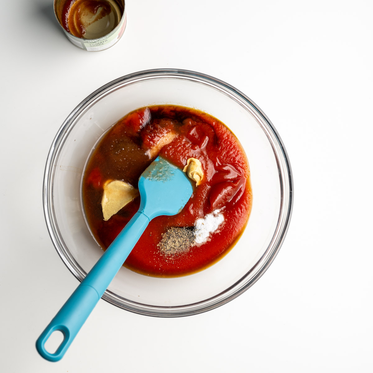 sauce ingredients in a glass bowl with a blue spatula.