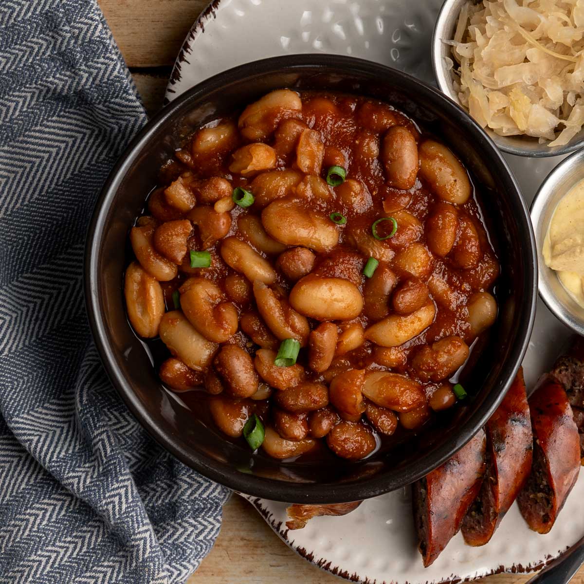black bowl of baked beans topped with chopped green onions.