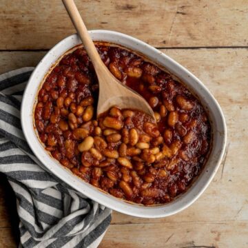 baking dish filled with low fodmap baked beans with a wooden spoon.