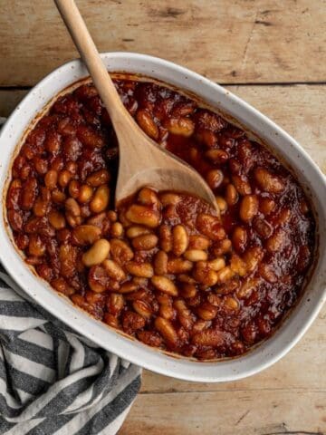 baking dish filled with low fodmap baked beans with a wooden spoon.