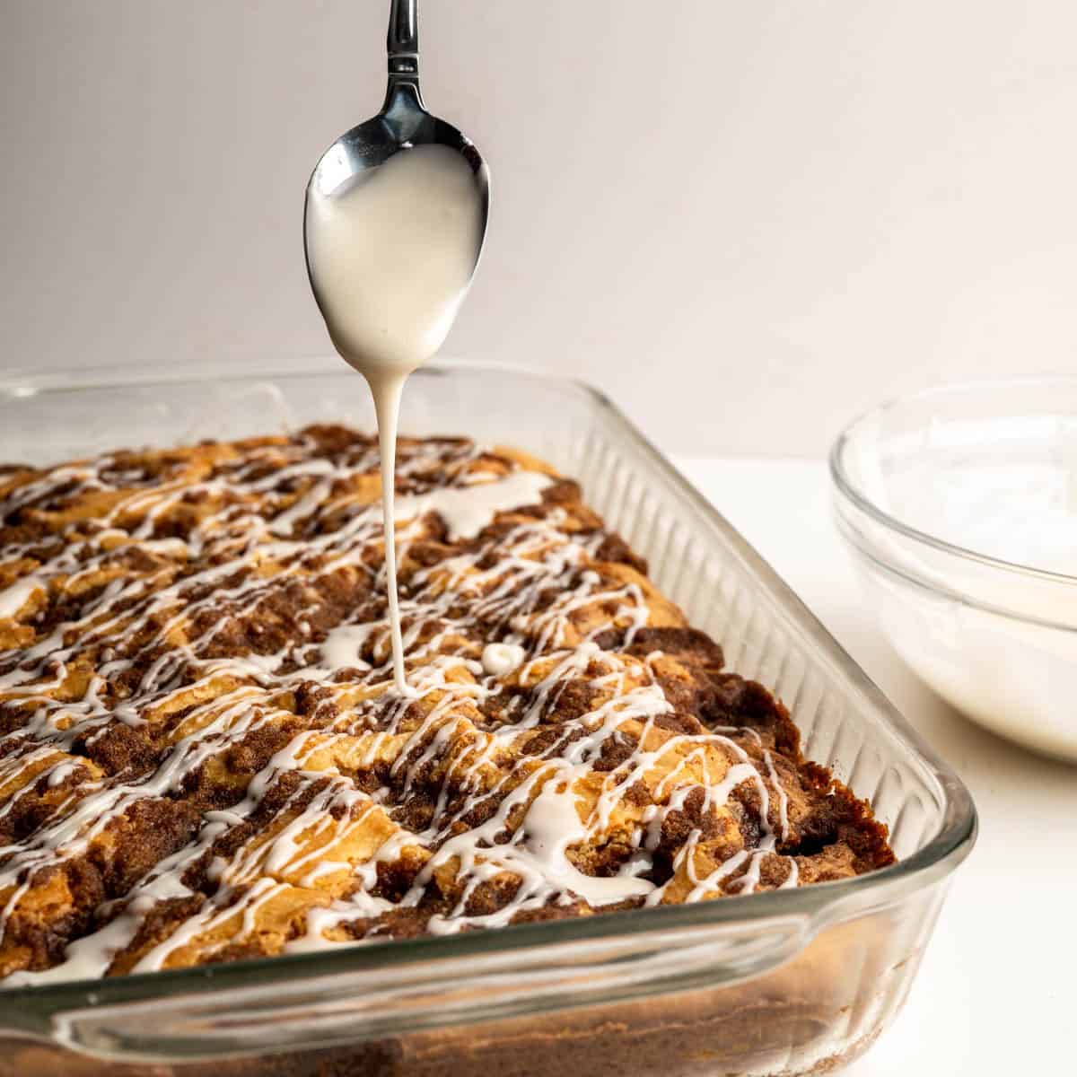 spoonful of glaze drizzled over a cooled cinnamon coffee cake.