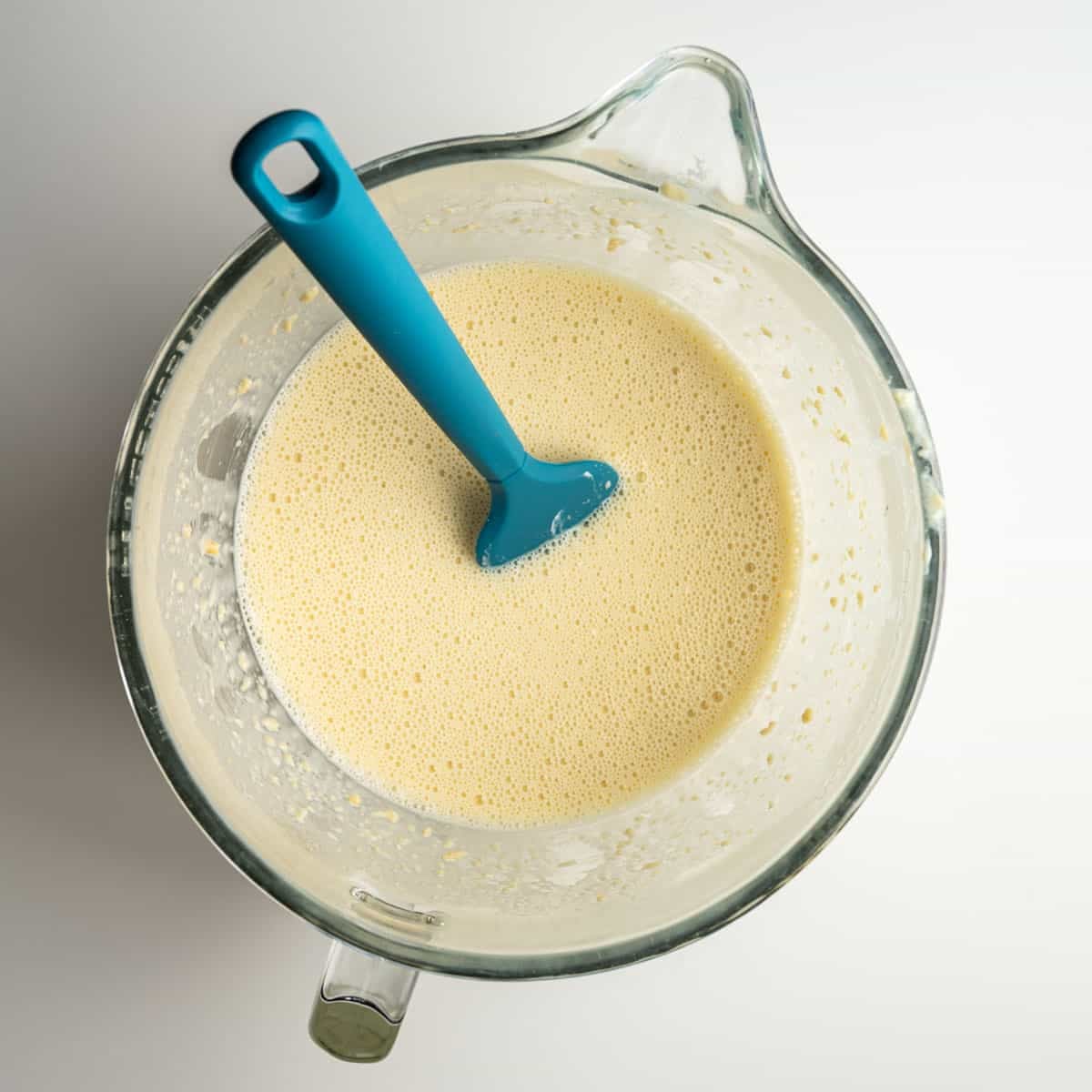 all wet ingredients in a mixer bowl with a blue spatula.