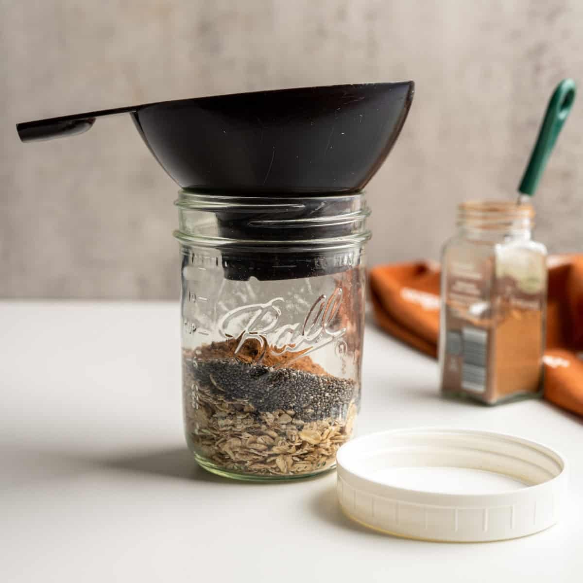 wide mouth mason jar with a funnel filled with dry ingredients.