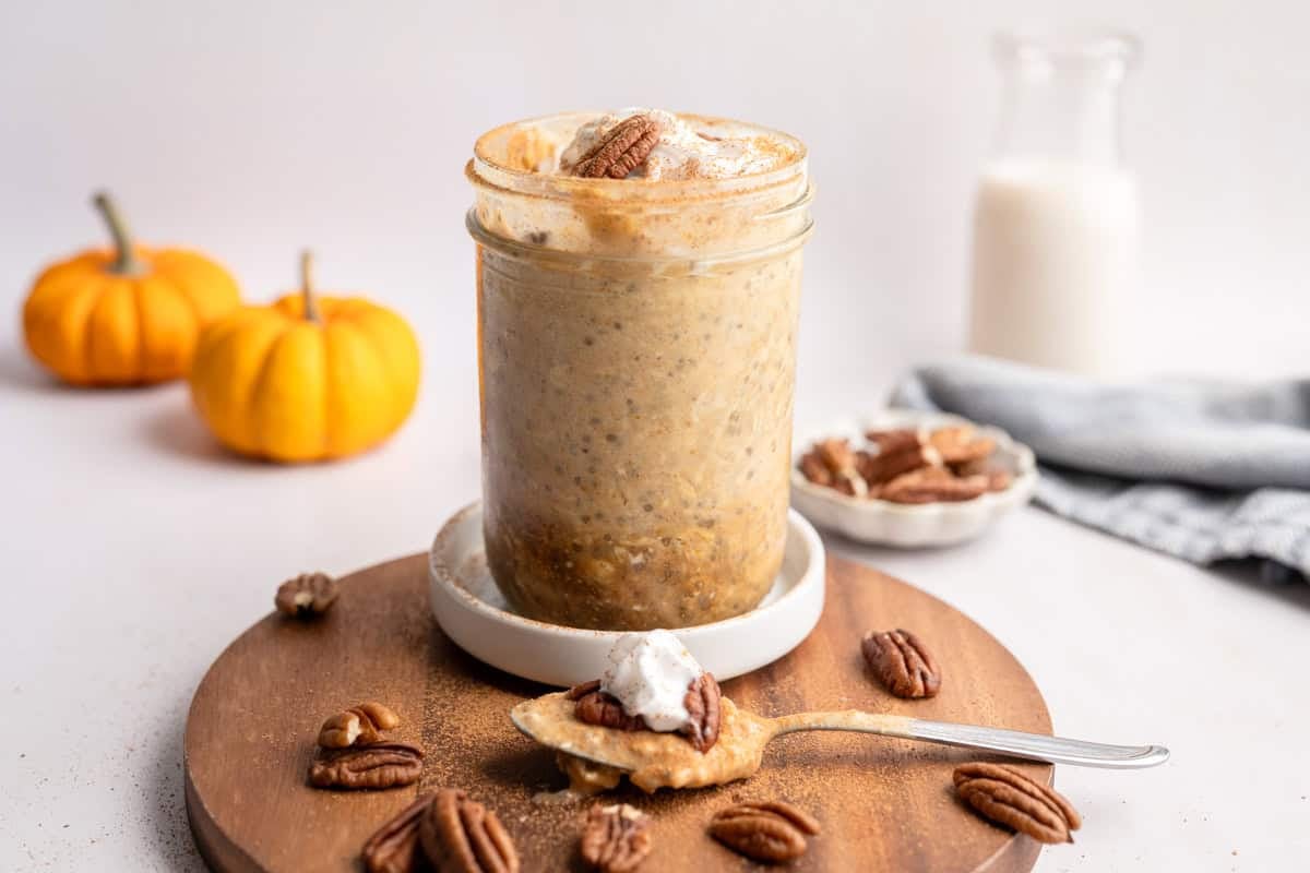 bite missing from pumpkin overnight oats topped with coconut whipped cream, cinnamon and pecans.