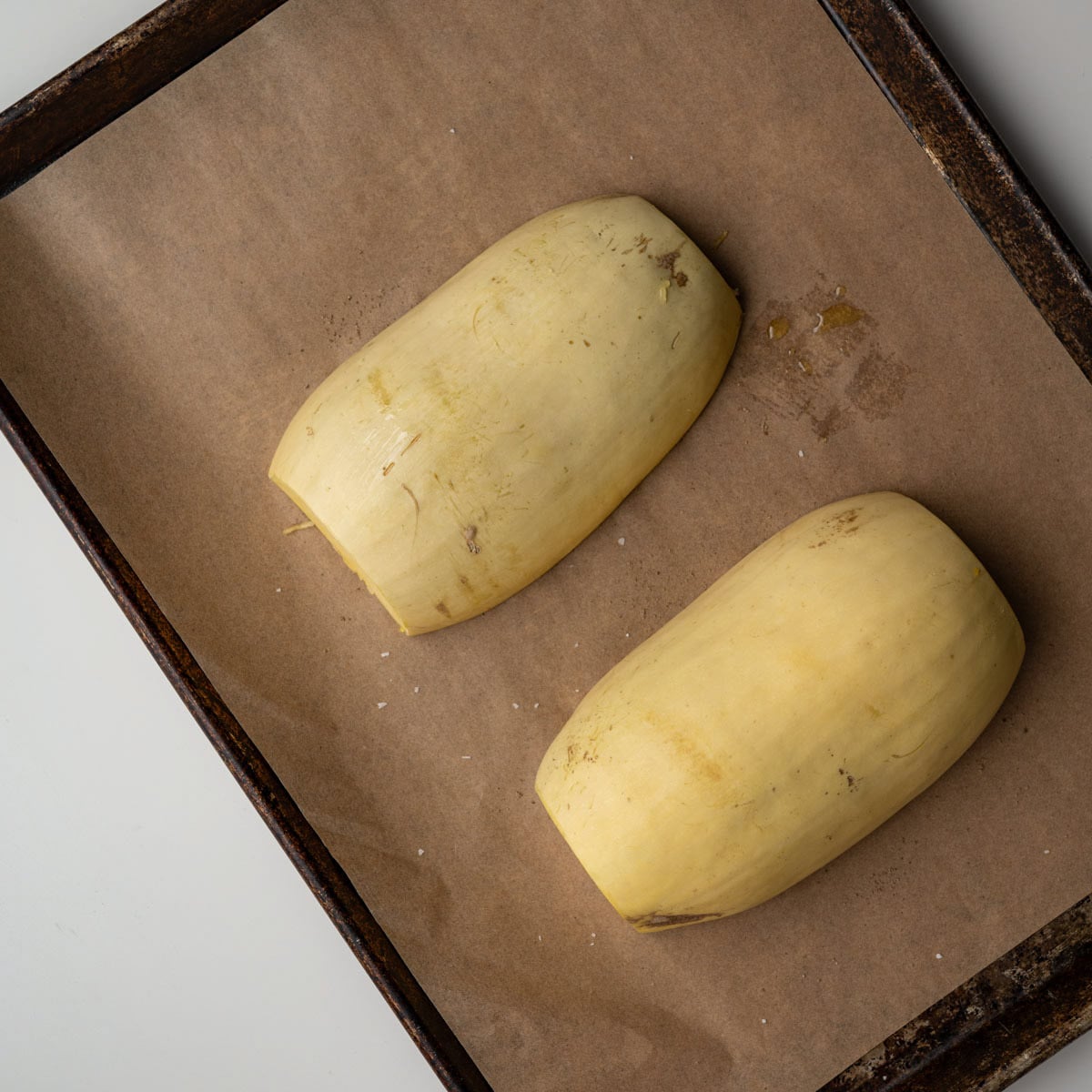 spaghetti squash halves skin side down on a baking sheet.