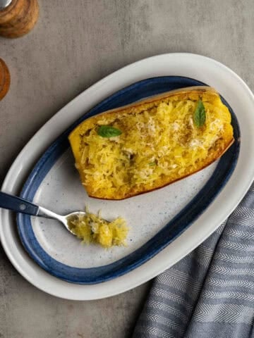 baked half of spaghetti squash on a platter with a fork.