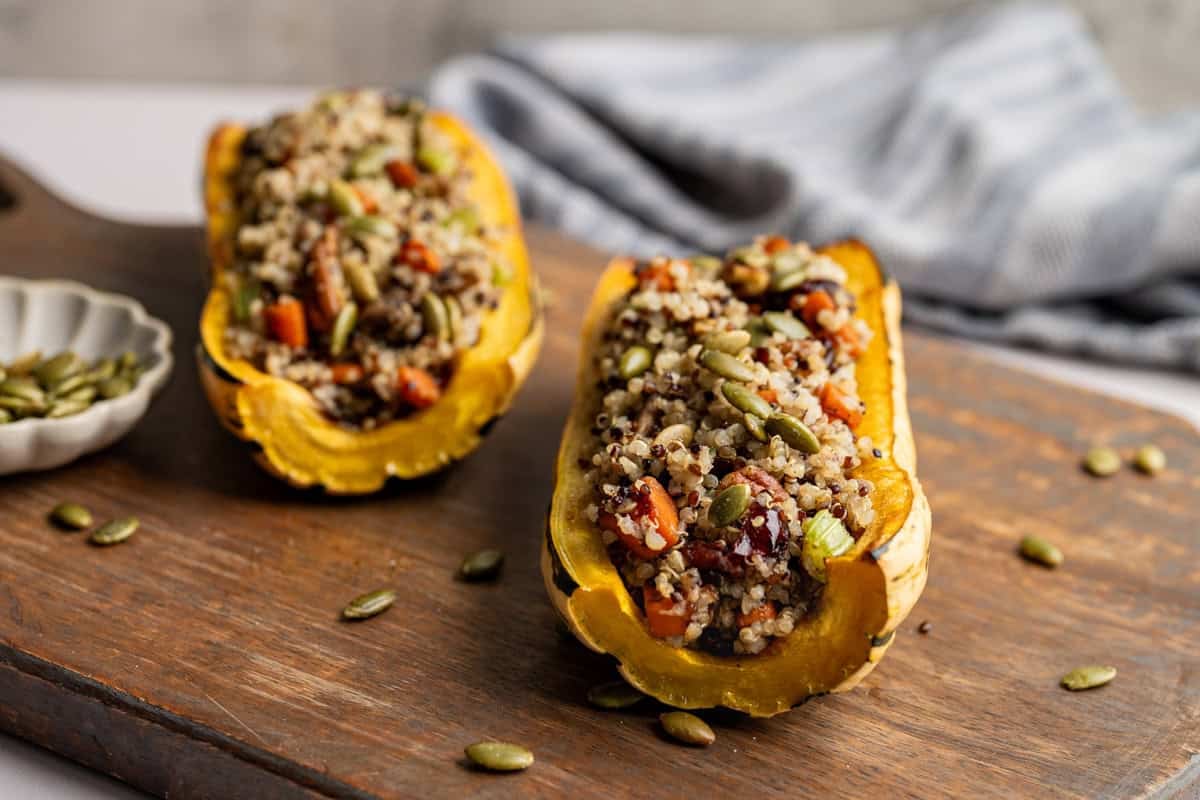 two delicata squash stuffed on a wooden board.