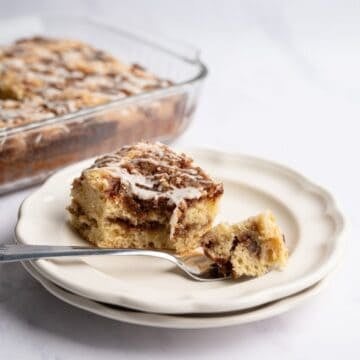 piece of cinnamon coffee cake with a bite on a fork with a baking pan in the background.