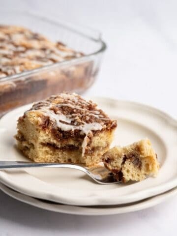 piece of cinnamon coffee cake with a bite on a fork with a baking pan in the background.