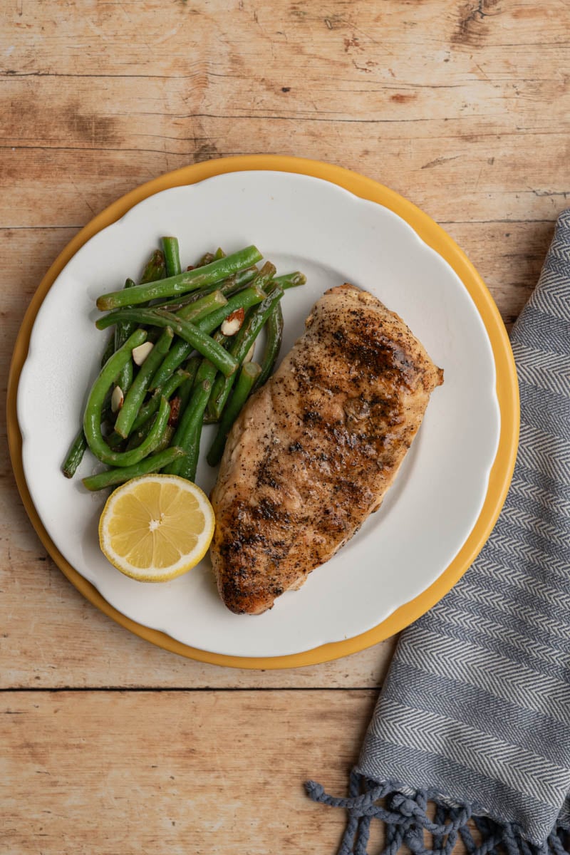 on a plate with green beans and a grilled chicken breast.