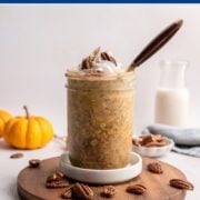 jar of overnight oats topped with coconut whipped cream, pecans and cinnamon.