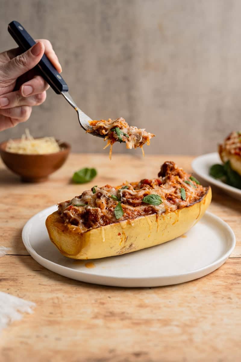 forkfull of stuffed spaghetti squash above a spaghetti squash boat.