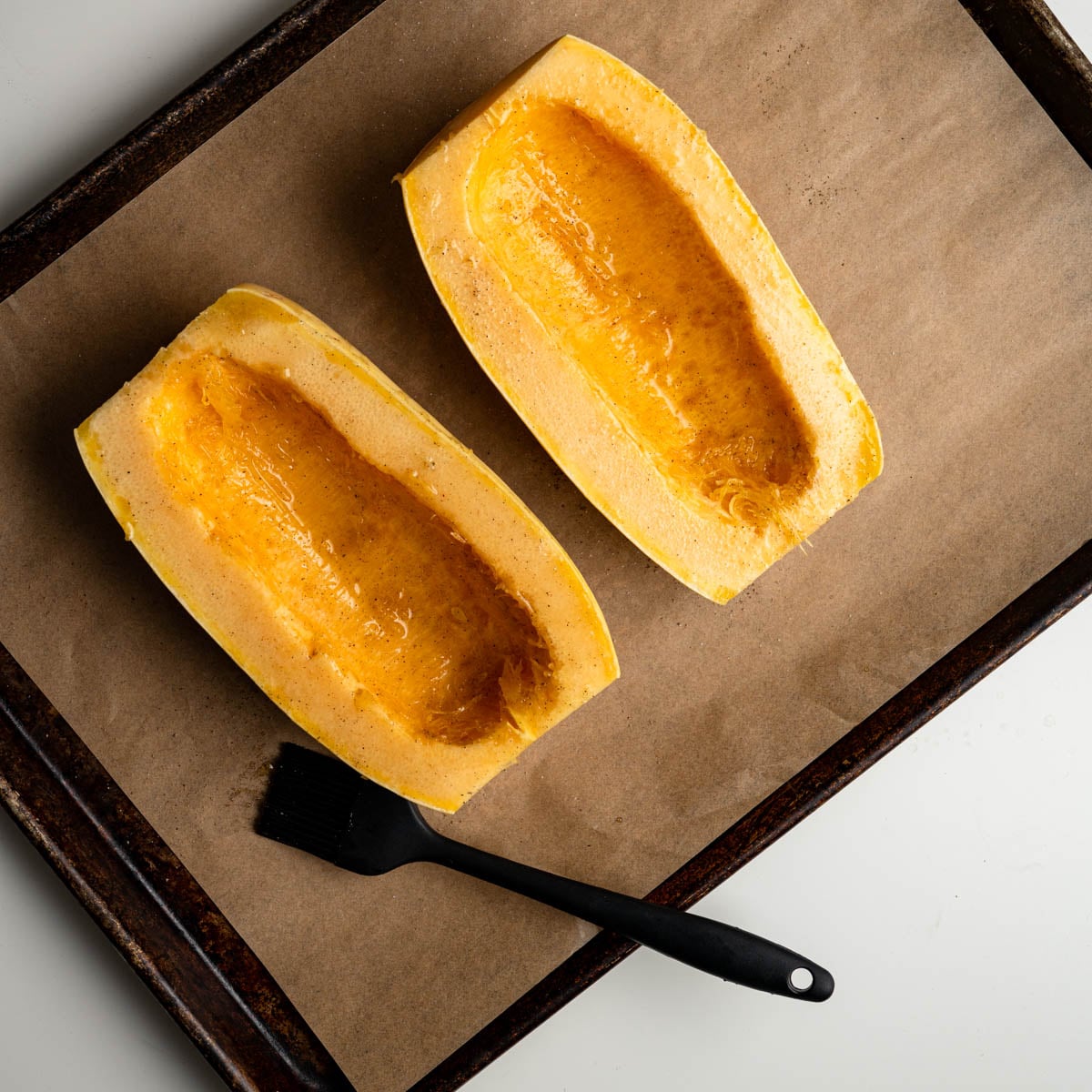 spaghetti squash havles brushed with garlic oil on a parchement covered baking sheet.