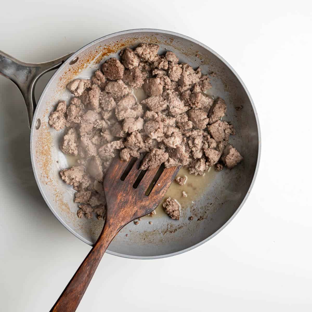 skillet with in the process cooking Italian turkey sausage.